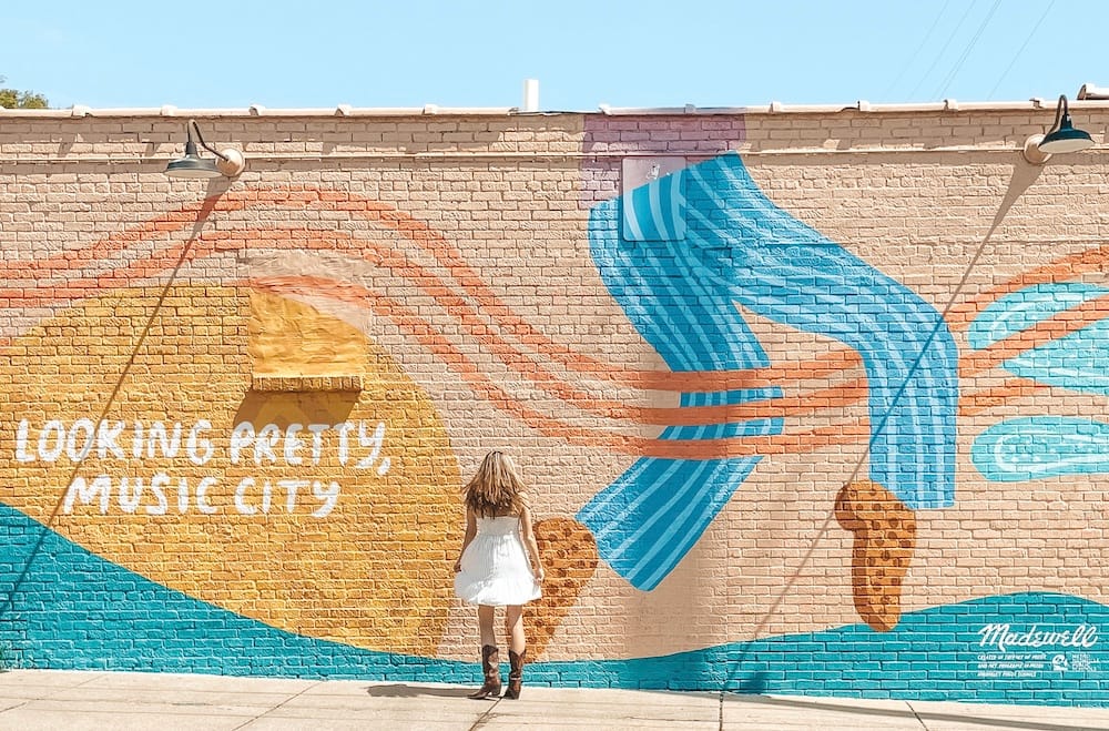 A girl in a white dress standing in front of a colorful mural in 12 South, one of the most fun things to do in Nashville