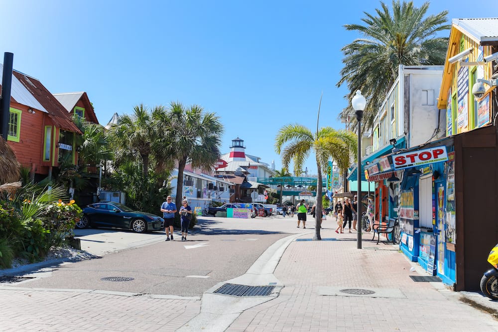 Several colorful buildings lining a walking path and street at John's Pass Village, one of the best cheap things to do in St. Pete