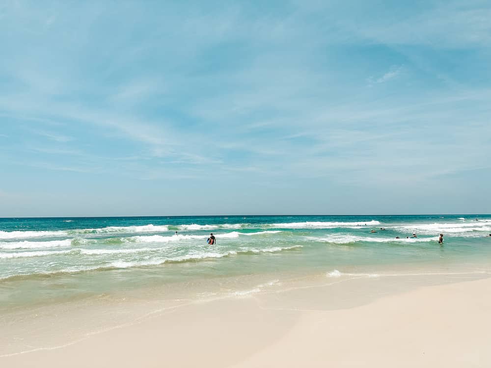 A few people in the turquoise waves just off the golden sand of Grayton Beach.