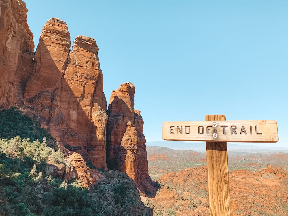 The end of trail sign at the end of the trail at Cathedral Rock, with a view of Cathedral Rock in the background.