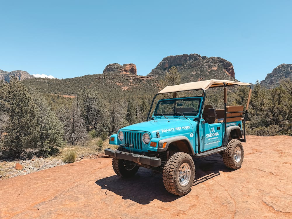 A blue Jeep in front of the red rocks in Sedona on an off-roading tour.