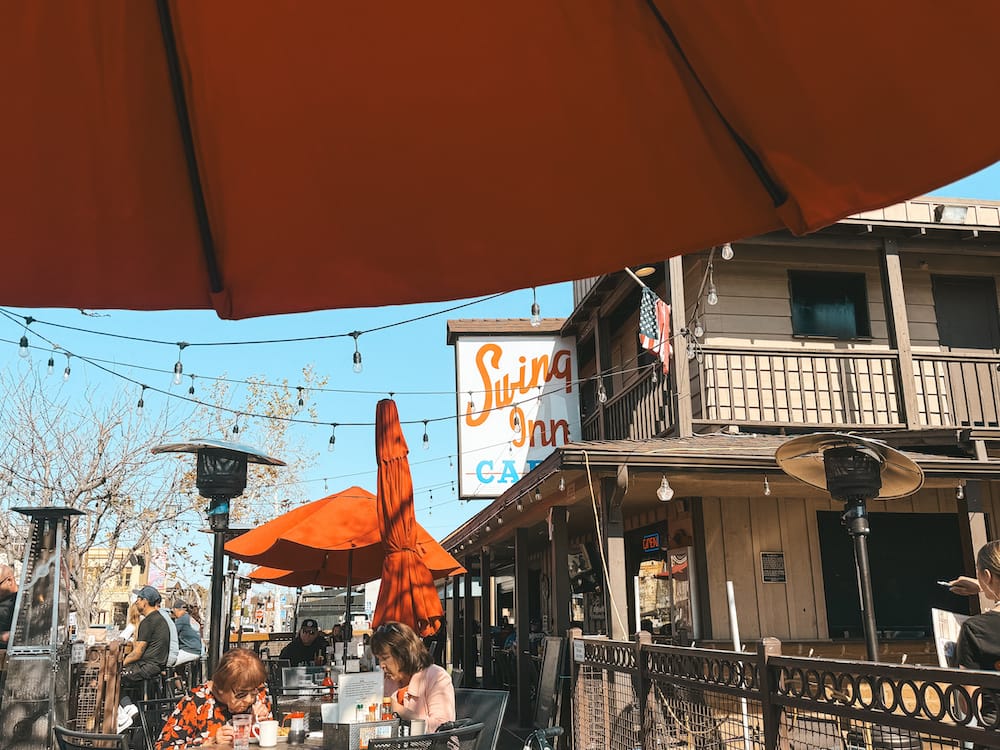 Swing Inn Cafe in Old Town Temecula, featuring bistro lights and red umbrellas.