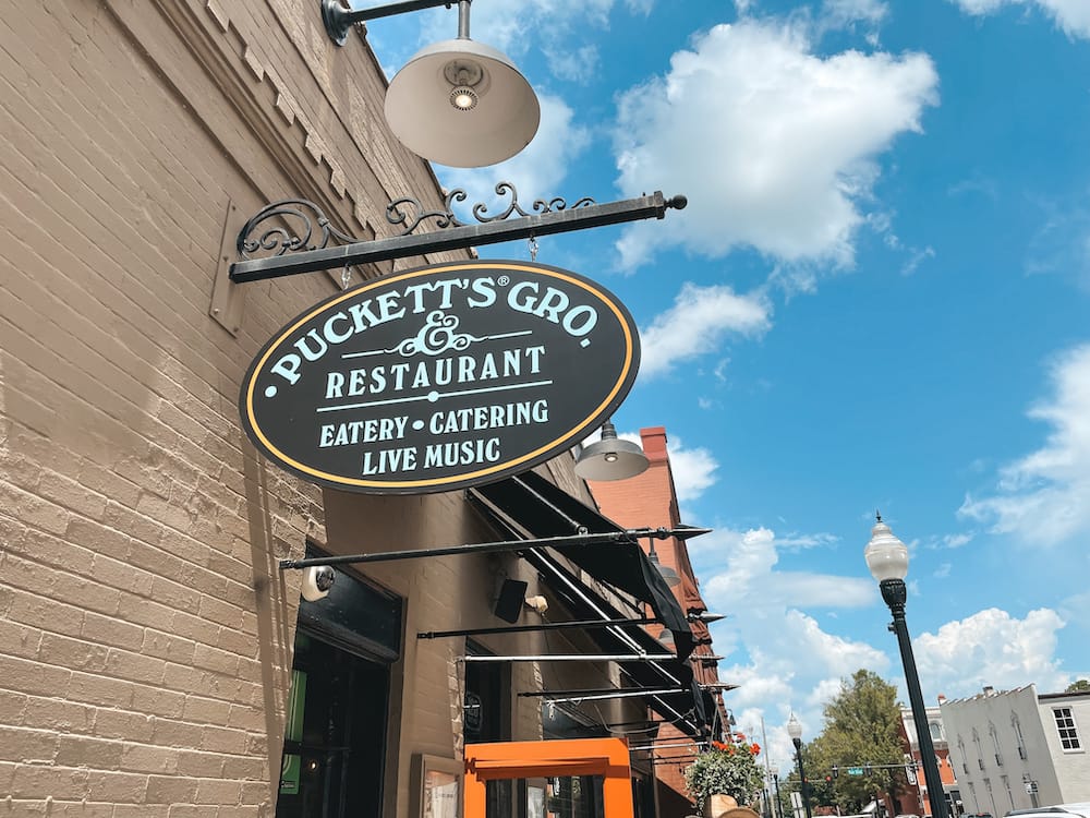 The exterior of Puckett's Grocery & Restaurant in Franklin with a sign that promotes an eatery, catering, and live music