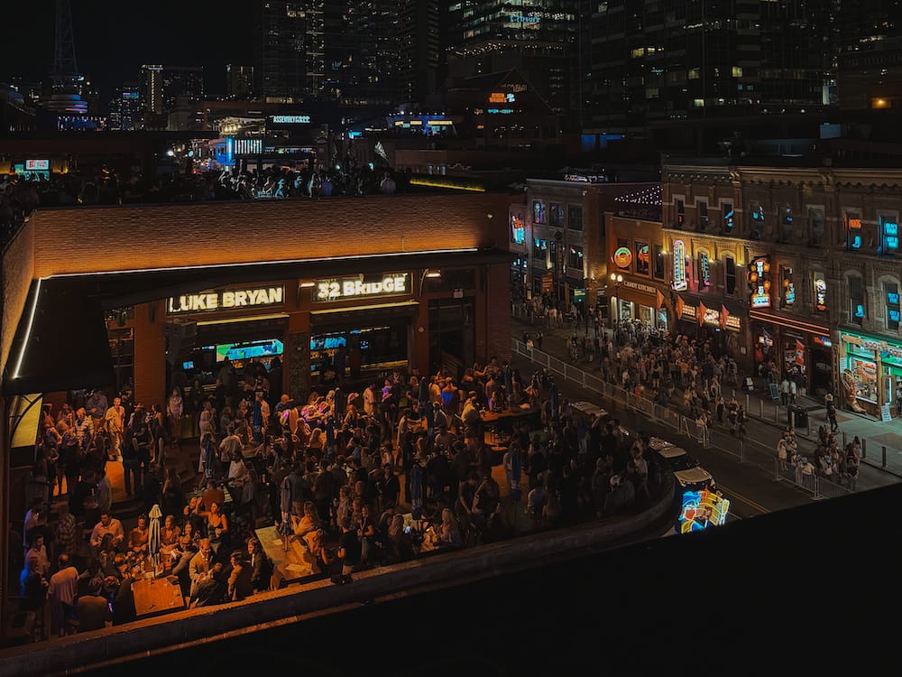 A view of the neon signs and rooftop bars on Broadway Street at night.