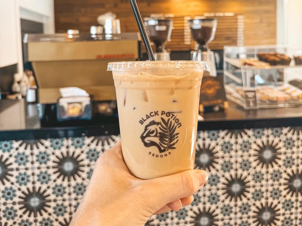 A cup of iced coffee in front of a coffee bar with blue, black, and white tile in Sedona.