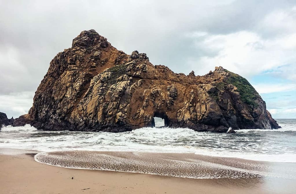 A rocky outcropping on a golden sand beach in Central California on a cloudy, overcast day