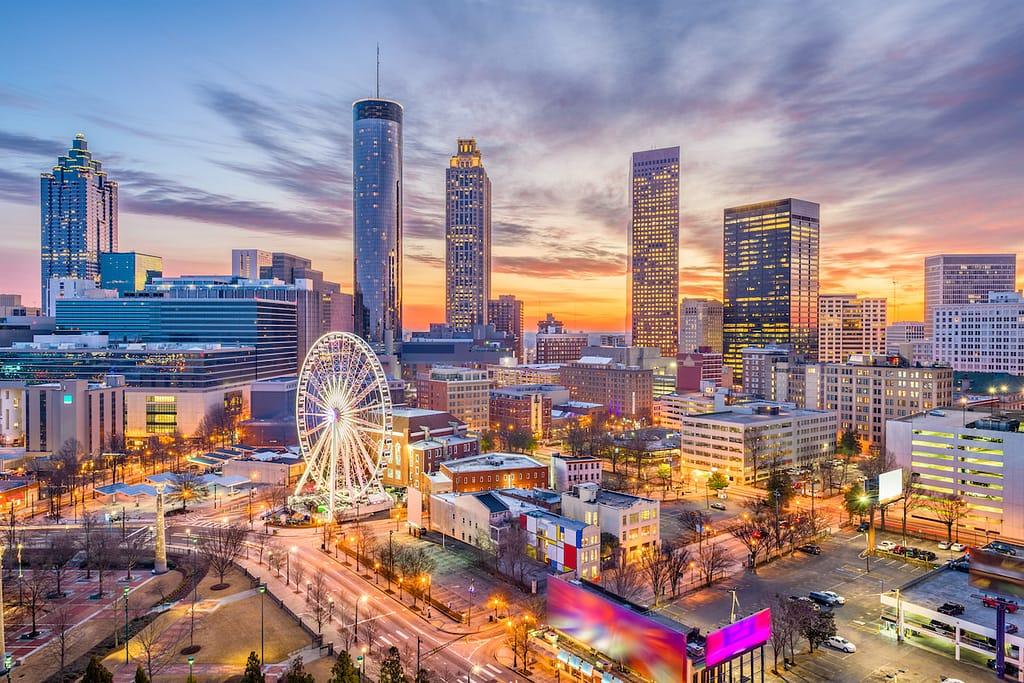 The Atlanta skyline, featuring a ferris wheel, tall skyscrapers, and colorful lights