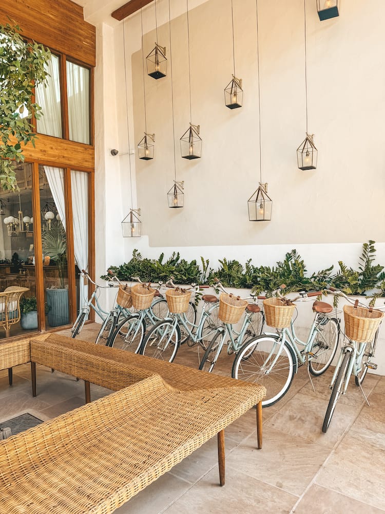 A white wall covered with hanging lanterns with bikes with wicker baskets sitting in front of it at The Scott Resort in Old Town Scottsdale