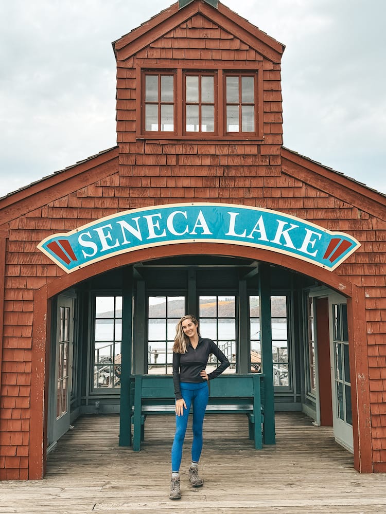 A woman in activewear standing in front of the Seneca Lake Harbor in Downtown Watkins Glen