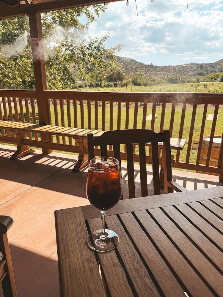 A red glass of sangria sitting on a wooden table at DA Ranch, one of the best wineries to visit during a day trip to Sedona.