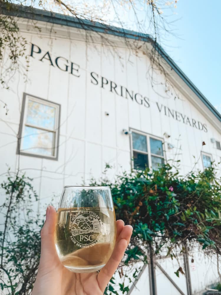 A chilled glass of white wine in front of the whitewashed barn turned winery in the Verde Valley called Page Springs Vineyards.