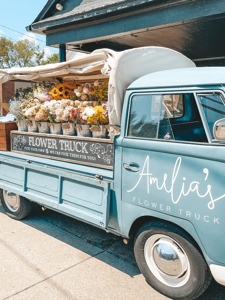 A powder blue pickup truck filled with buckets of flowers, called Amelia's Flower Truck, in 12 South