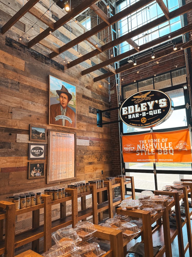 The wooden interior for Edley's Bar-B-Que, with photos on the wall and a orange sign that says "The Home of Nashville-Style BBQ"