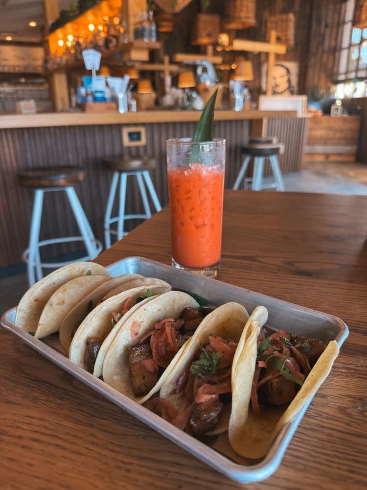 A plate with five tacos and a tropical drink at a Mexican restaurant in Nashville