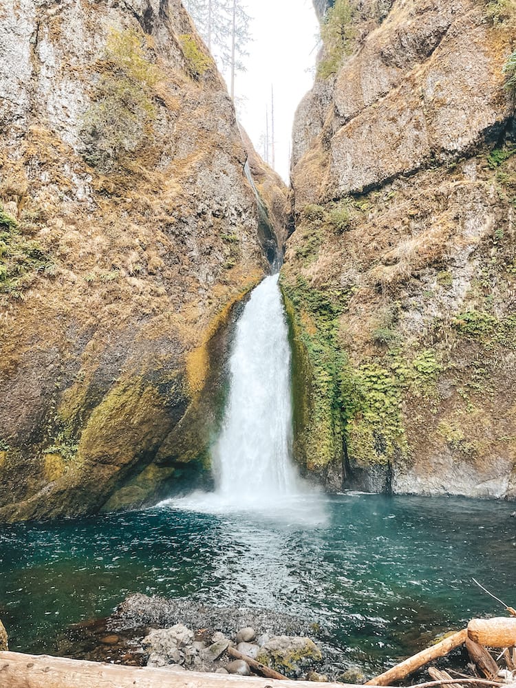 A white foaming waterfall cascading into a blue pool between two rocks