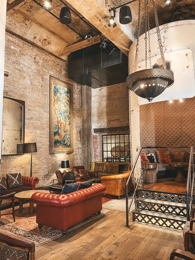 One of the dining areas in Hotel Emma, with a red leather couch, beautiful, old-style paining, and brickwork on the walls.