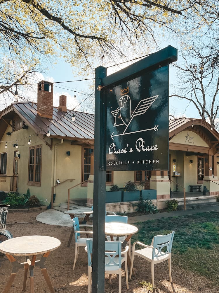 A sigh for Chase's Place Cocktails + Kitchen in front of a historic green and brown building.
