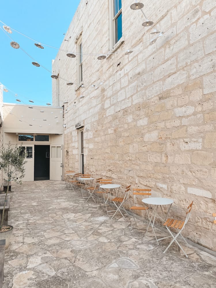 An alleyway in Fredericksburg with stone floors and white brick walls.