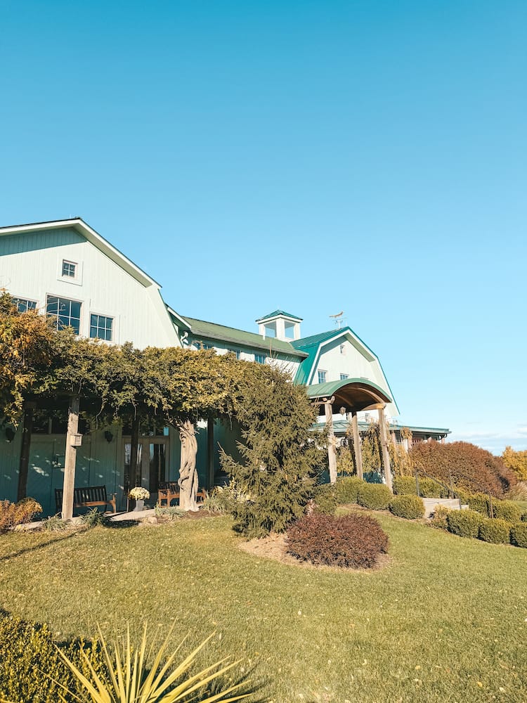 A charming, modern green and white barn-themed winery in the Finger Lakes surrounded by lush greenery