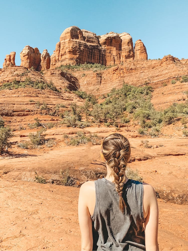 A woman with braided hair looking at Cathedral Rock, one of the most famous attractions in Sedona