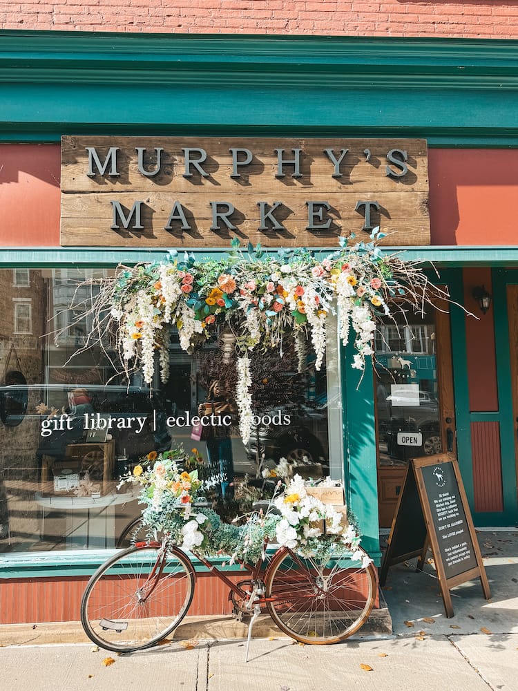 The storefront of Murphy's Market in Downtown Geneva, with a bike covered in flowers in front of the store.