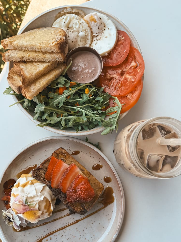 A breakfast spread with French toast, eggs, salad, tomatoes, toast, and iced coffee at one of the best restaurants in Sedona.