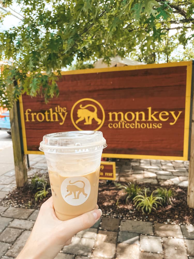 A cup of iced coffee in front of a sign for The Frothy Monkey Coffeehouse, one of the best coffee shops in Nashville, located in 12 South
