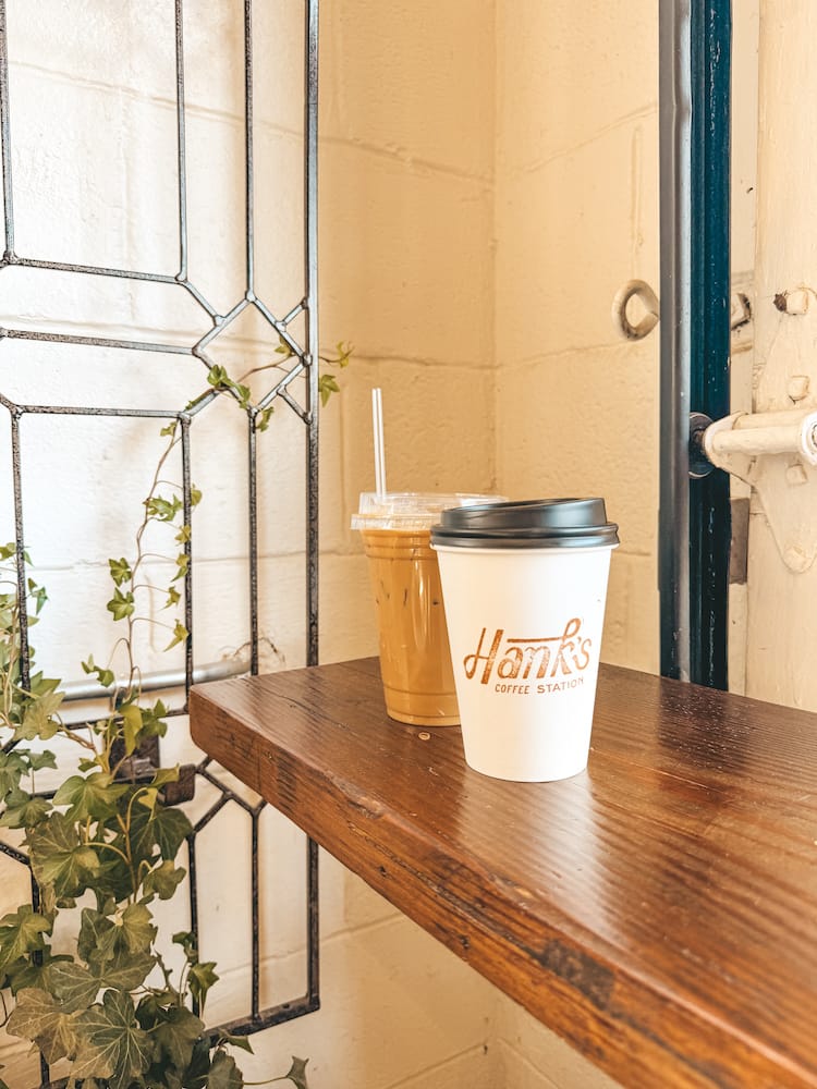 An iced coffee and hot coffee sitting on a wooden counter inside Hank's Coffee Station, one of the best coffee shops in Franklin