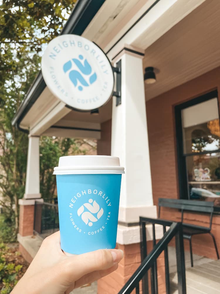 A blue cup of hot coffee in front of Neighborlily, a coffee and floral shop in Germantown in Nashville