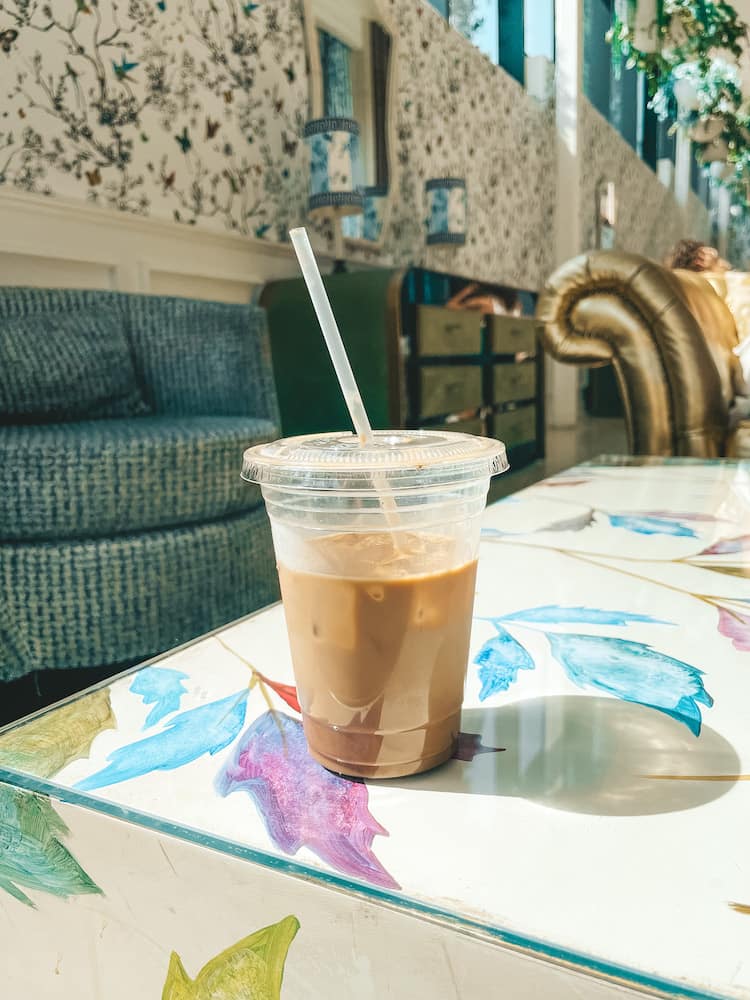 An iced coffee sitting on a table with colorful motifs at Poindexter Coffee, one of the best coffee shops in Nashville