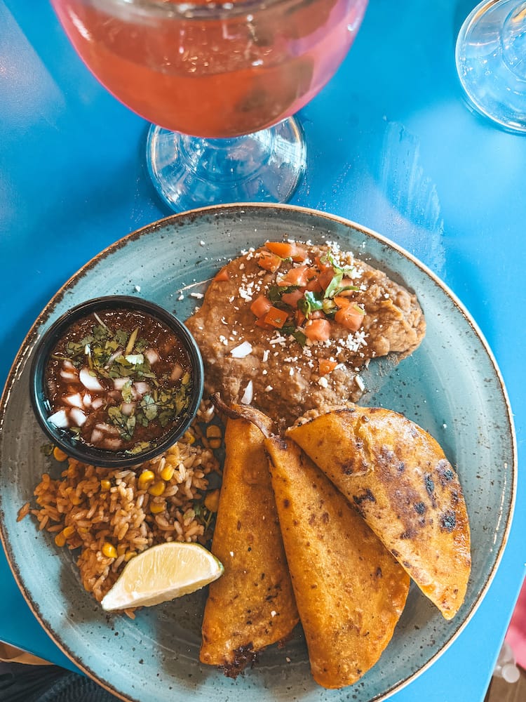 A plate with tacos, refried beans, rice, and sauce on a blue table at a Mexican food restaurant in Sedona