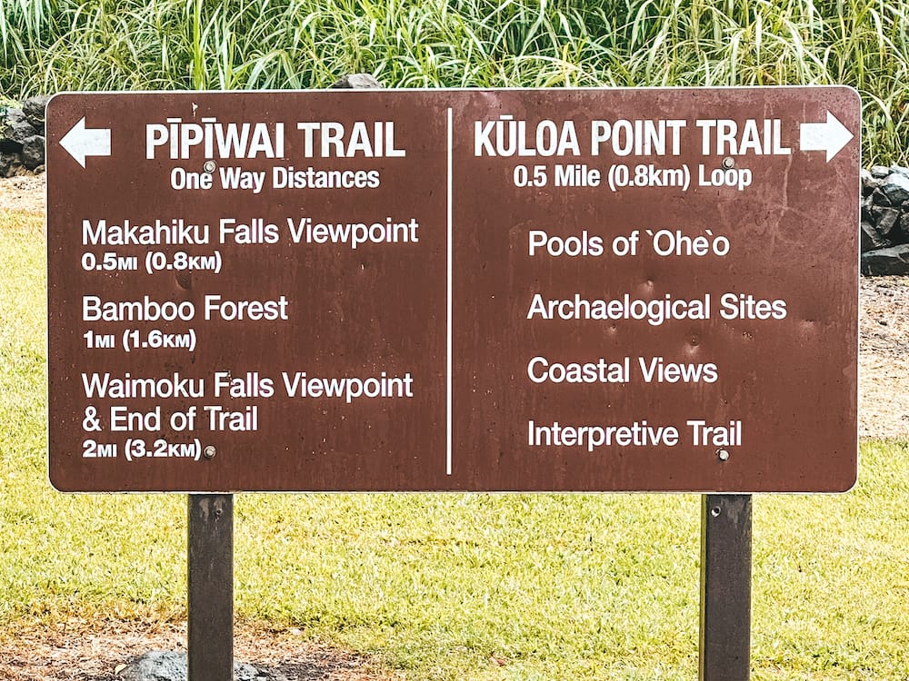 A brown sign telling visitors to go left for the Pipiwai Trail and right for the Kuloa Point Trail
