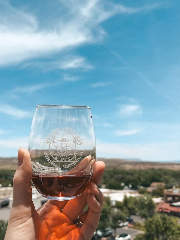 A glass of red wine in front of the skyline in Old Town Cottonwood from Merkin Vineyards Hilltop Winery & Trattoria