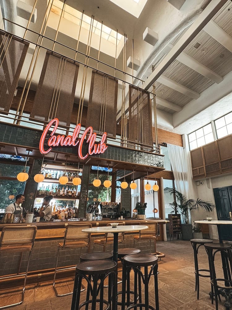 A bar with neon pink letters that says "Canal Club" with green tiling and yellow lights at The Scott Resort in Old Town Scottsdale