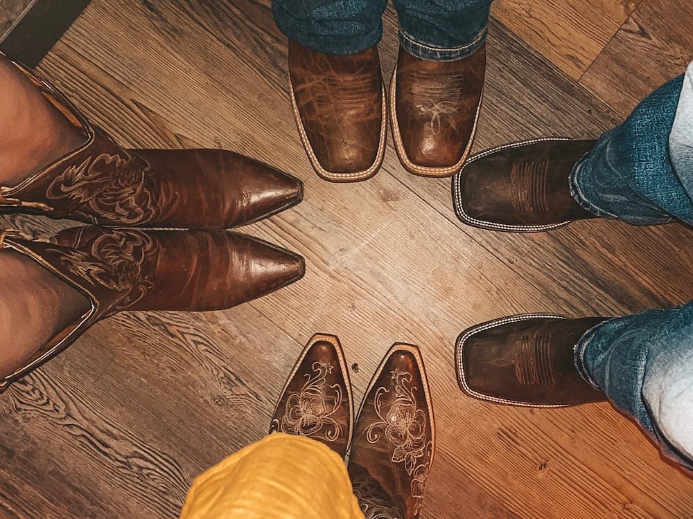 Four pairs of cowboy boots standing on a wooden floor at a country bar in Scottsdale
