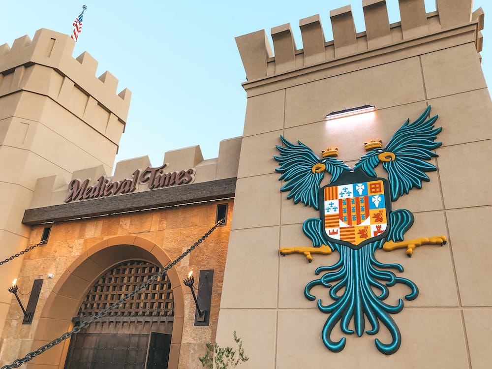 The castle-like exterior of Medieval Times in Scottsdale features a drawbridge and a crest of two birds wearing crowns.