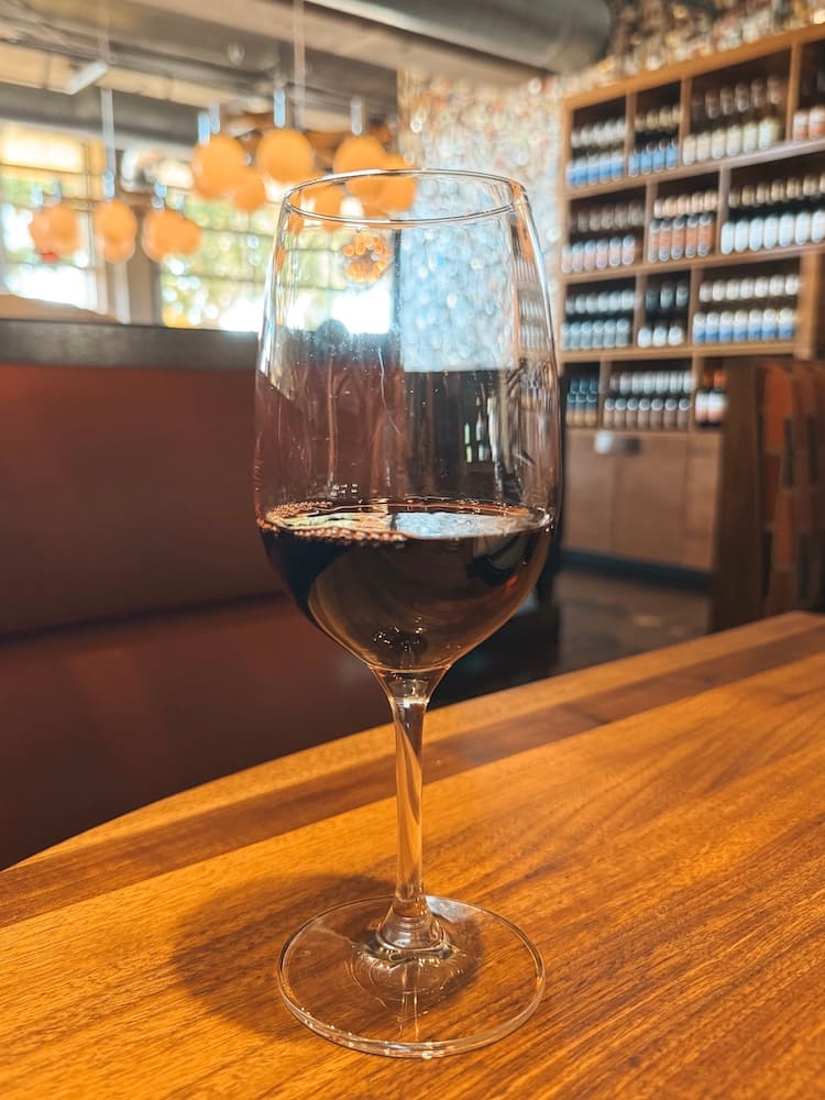 A glass of red wine sitting on a wooden table at Postino in Scottsdale