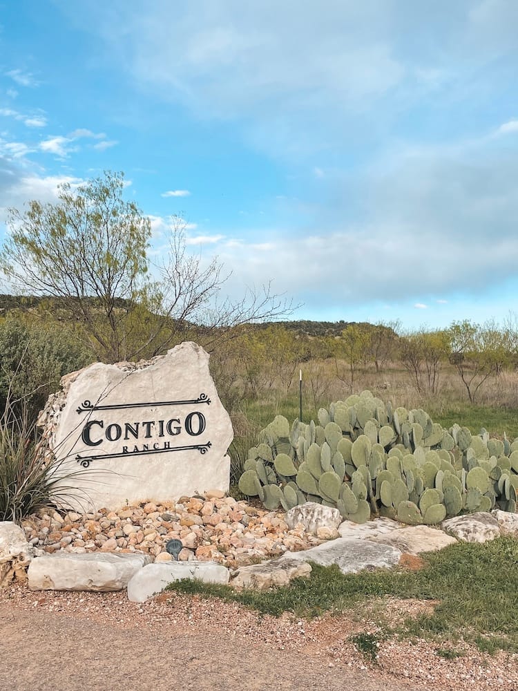 A rock that says Contigo Ranch with a cactus next to it.