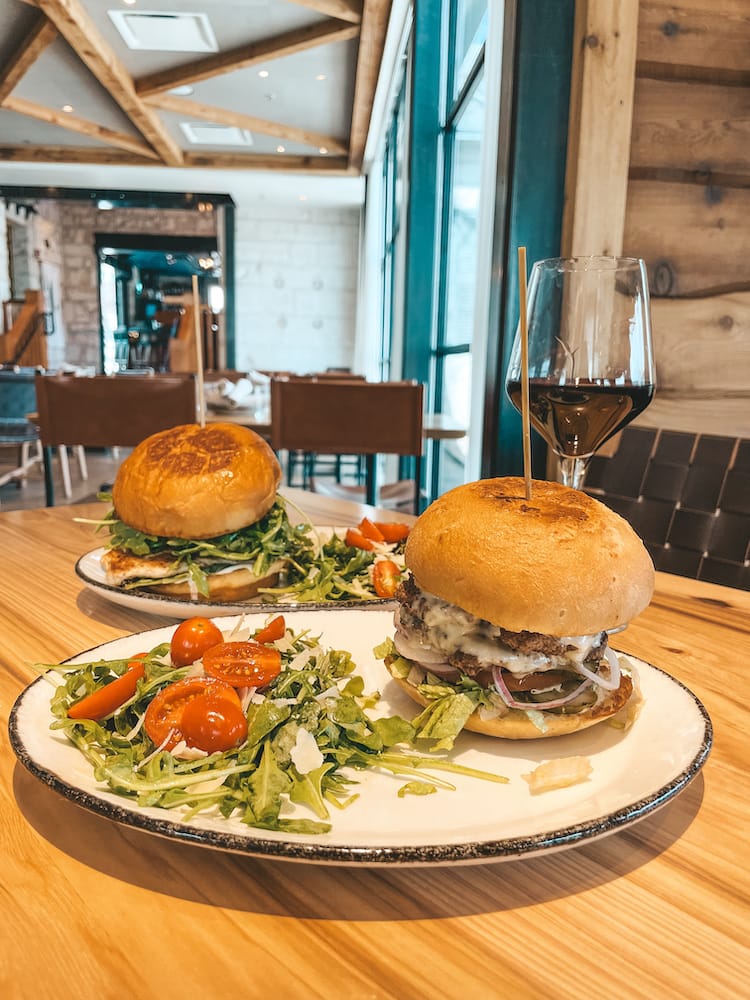 Two burgers and a glass of red wine sitting on a table at a trendy restaurant in Fredericksburg, TX