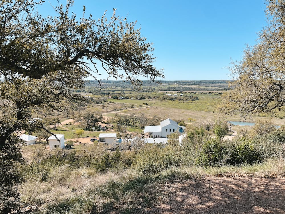A beautiful scenic lookout over the Texas Hill Country at Contigo Ranch, with white cottages and a lake in the background.