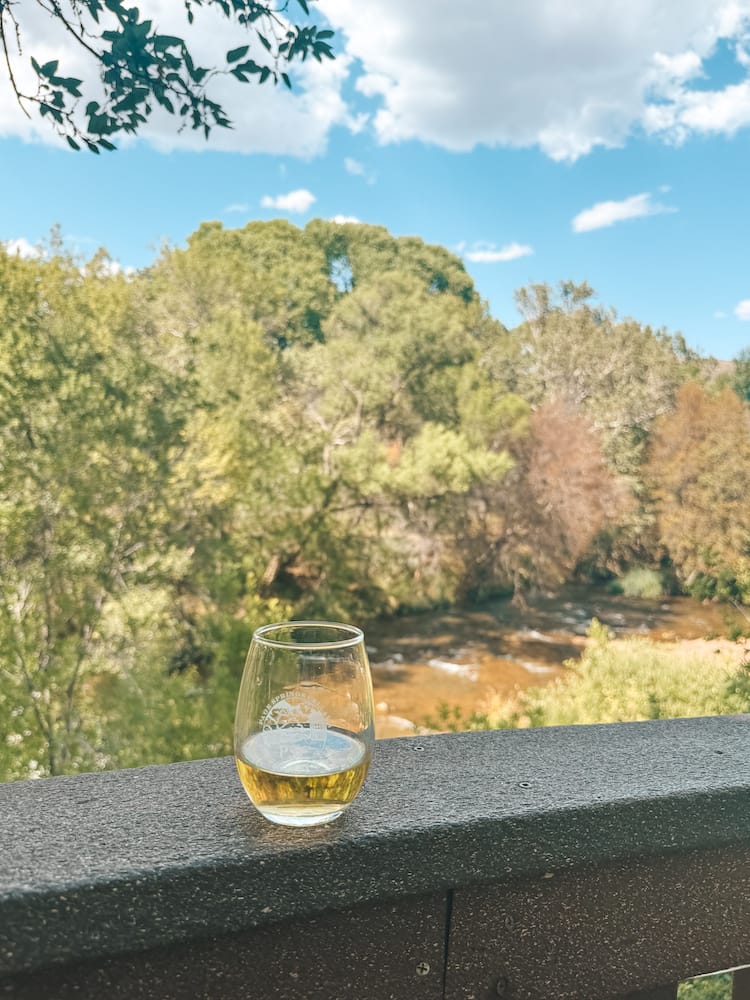 A glass of white wine sitting on a ledge overlooking Oak Creek in Sedona.