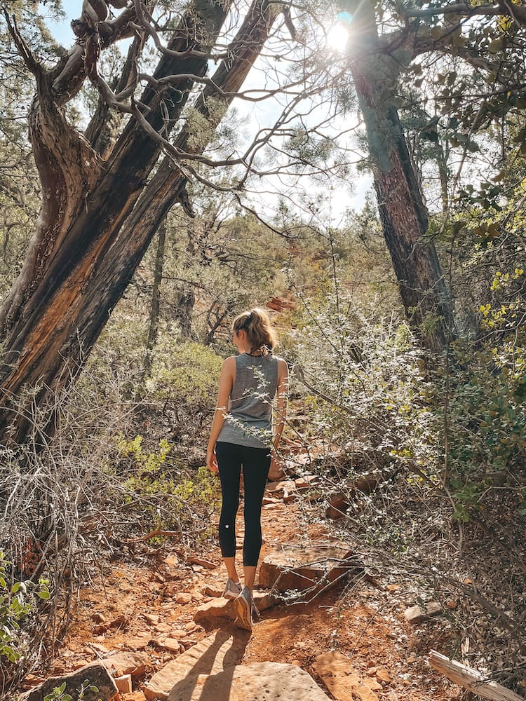 A woman in a gray tank top and black leggings hiking on Solider Pass Trail, one of the best hikes in Sedona.