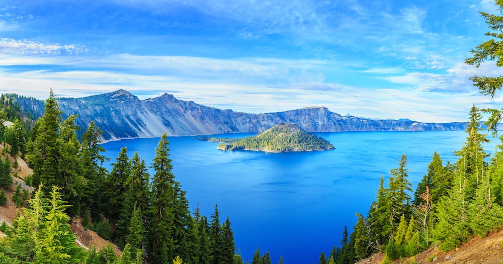 A view of the blue water and greenery surrounding Crater Lake in Oregon.