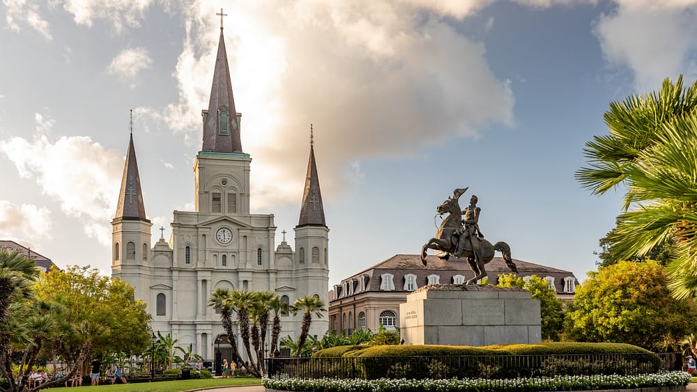 A photo of an ornate church and statue of a man riding on a horse in Jackson Square in New Orleans - one of the best places to visit in the USA in 2023