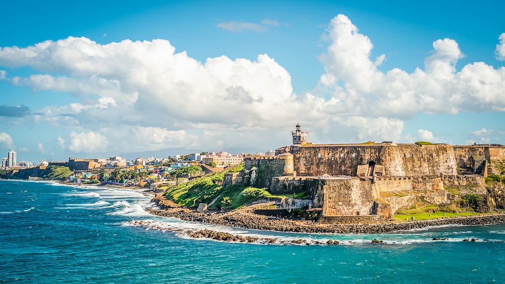 A gorgeous view of Old San Juan from the coast with bright blue water and ancient architecutre, one of the best places to visit in February in the USA.