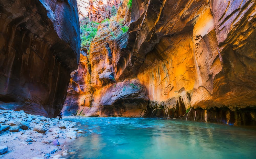 The Narrows in Zion, with orange canyon walls surrounding turquoise blue water.