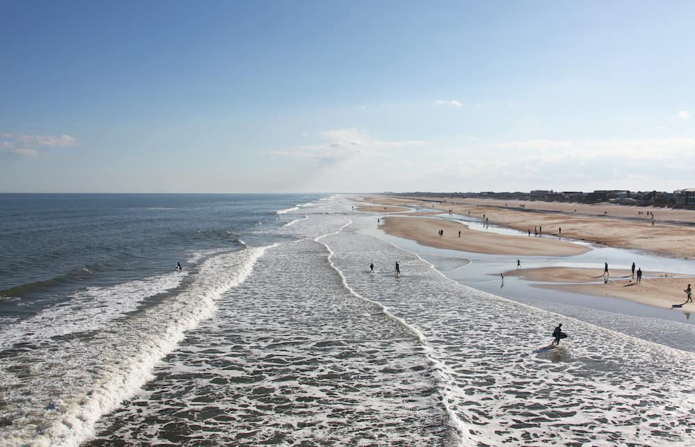 A aerial view of the beach at St. Augustine with surfers coming in and out of the waves.