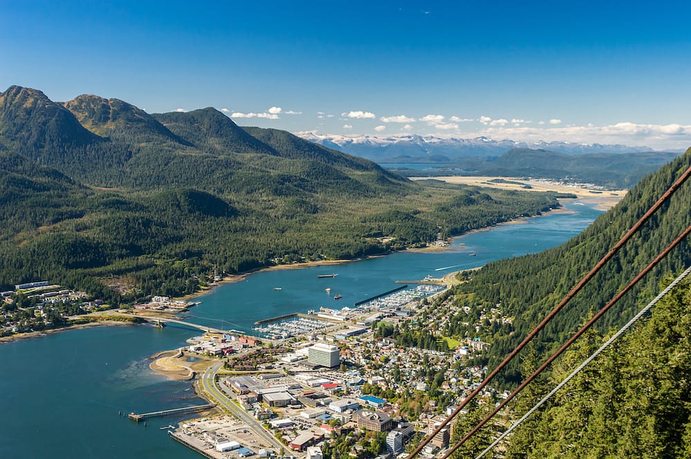 The green mountains, blue water, and small town of Juneau, Alaska, from the standpoint of an aerial tram in the air.