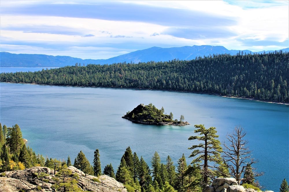 The clean blue waters of Lake Tahoe surrounding by green trees and rocky formations