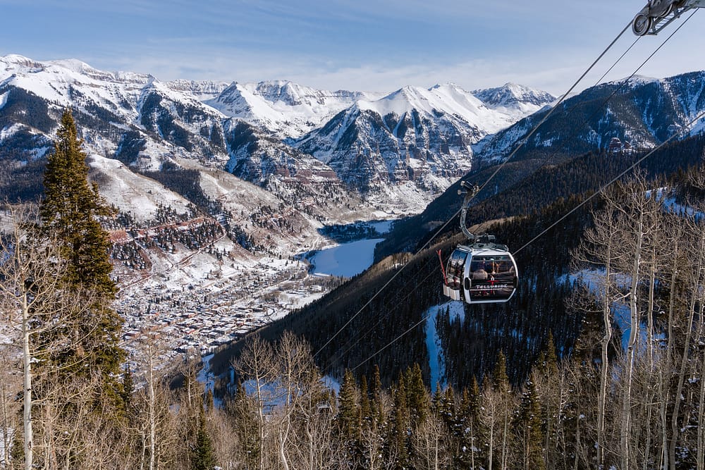 A sky gondola gliding into Telluride, Colorado, covered in snow, one of the best places to visit in the USA in February.